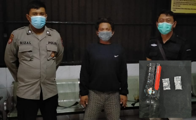 Setyo Wisnu Fardana (21), pengamen yang menyimpan sabu dalam senter, diapit dua lpetugas kepolisian Surabaya.