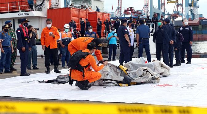 Petugas KPLP dan Basarnas memeriksa barang temuan yang diduga serpihan pesawat Sriwijaya Air SJ 182 di Dermaga JICT 2, Jakarta, Minggu (10/1/2021).