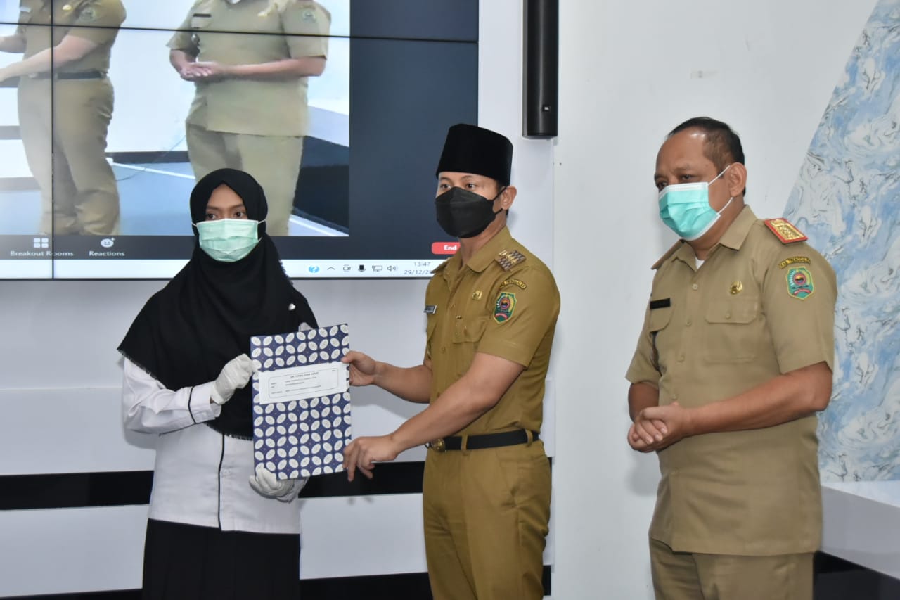 SAH: Bupati Trenggalek Mochamad Nur Arifin saat menyerahkan SK PNS kepada salah satu PNS dalam sebuah seremoni pengangkatan PNS secara virtual di Gedung Smart Center, Selasa (29/12/2020). | BCSJ