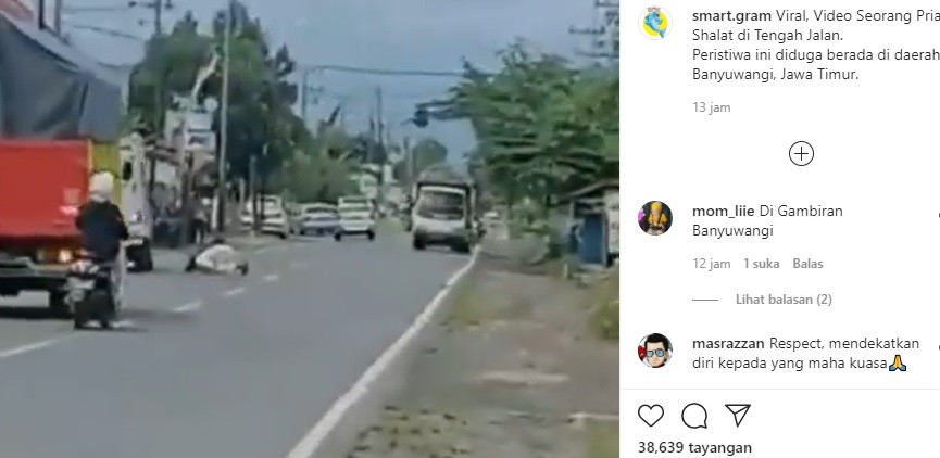 Screen shit pria berjubah putih salat di tengah jalan raya. 