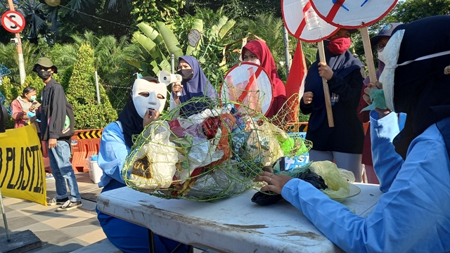 Aksi teatrikal makan palstik di depan Gedung Grahadi.
