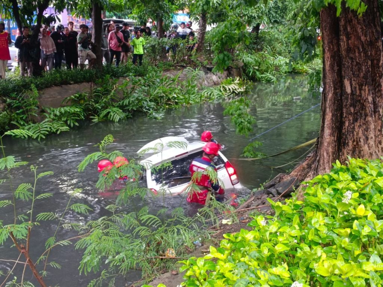 Petugas mengevakuasi mobil yang masuk sungai akibat ditabrak mobil di kawasan Kenjeran, Surabaya Senin (23/12/2024).