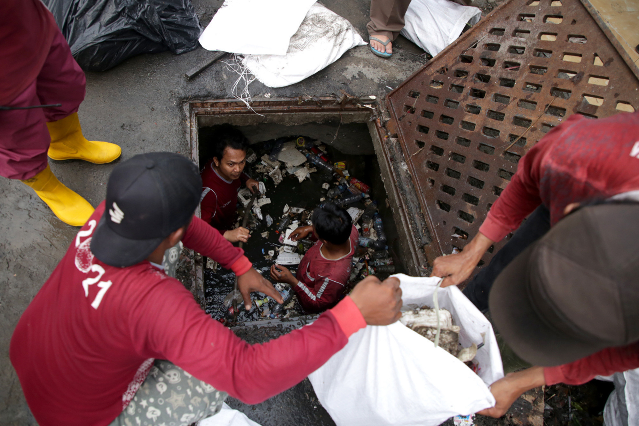 Petugas membersihkan sampah di saluran