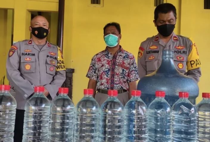 AZ, penjual miras jenis ciu beserta barang bukti berupa 9 botol 1,5 liter terisi penuh miras saat Konferensi Pers di Mapolsek Lakarsantri Surabaya, Senin (25/7/2022)