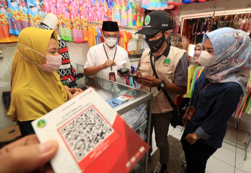 Pimpinan Bank Jatim Cabang Pasuruan Deddy Adjie Wijaya (Baju Putih) memantau uji coba pelaksanaan e-Retribusi di Pasar Kebonagung, Kota Pasuruan. (Kominfo Jatim)
