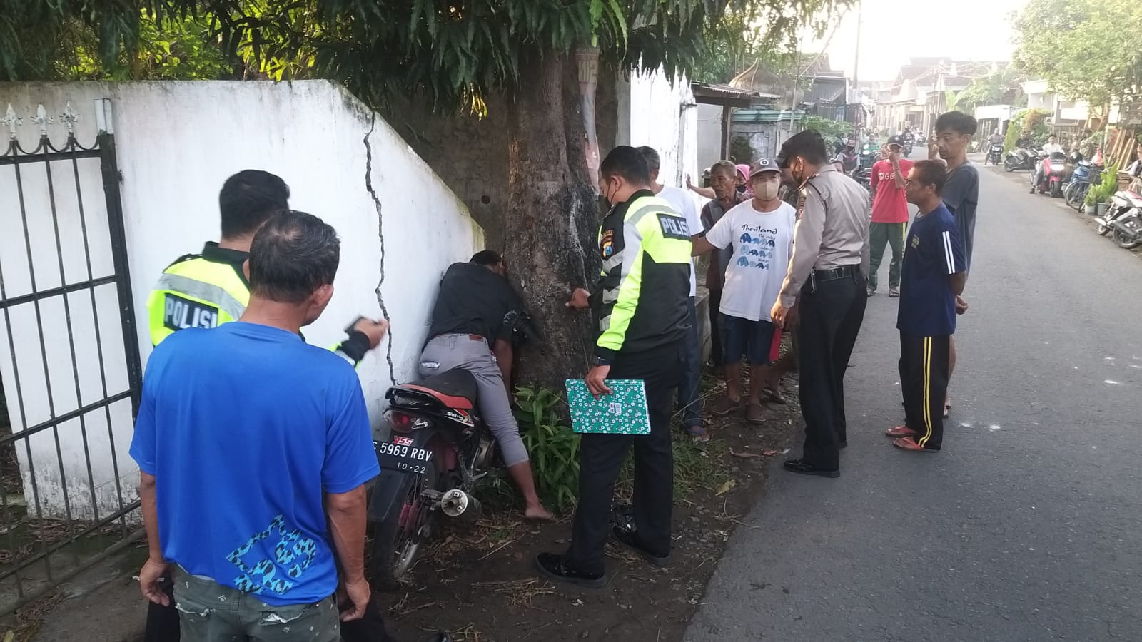 RF dan motornya terjepit di sela tembok makam dan pohon