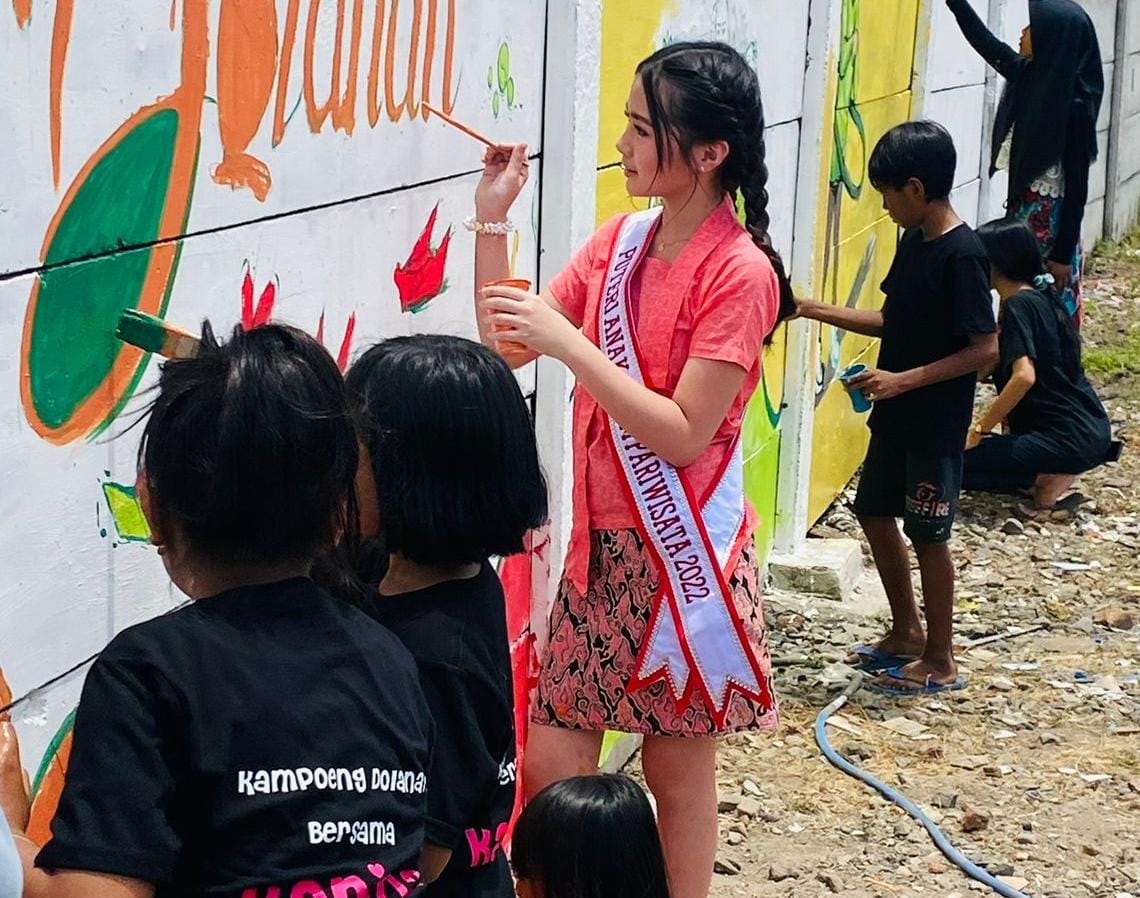 Putri Anak Jatim Pariwisata, Karina Aliya Afandi (12) saat menggambar mural di tembok dan bermain permainan tradisional di Kampung Dolanan Surabaya.