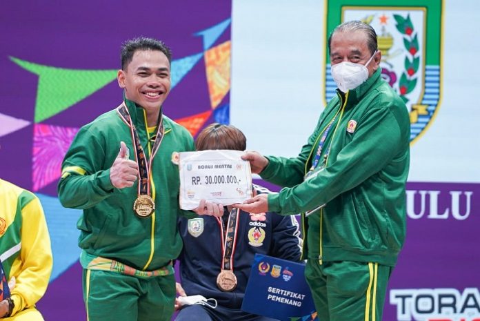 Eko Yuli (kiri) menerima bonus mentas dari Ketua Umum KONI Jatim Erlangga Satriagung usai meraih emas di kelas 67 kg, Rabu (6/10/2021).