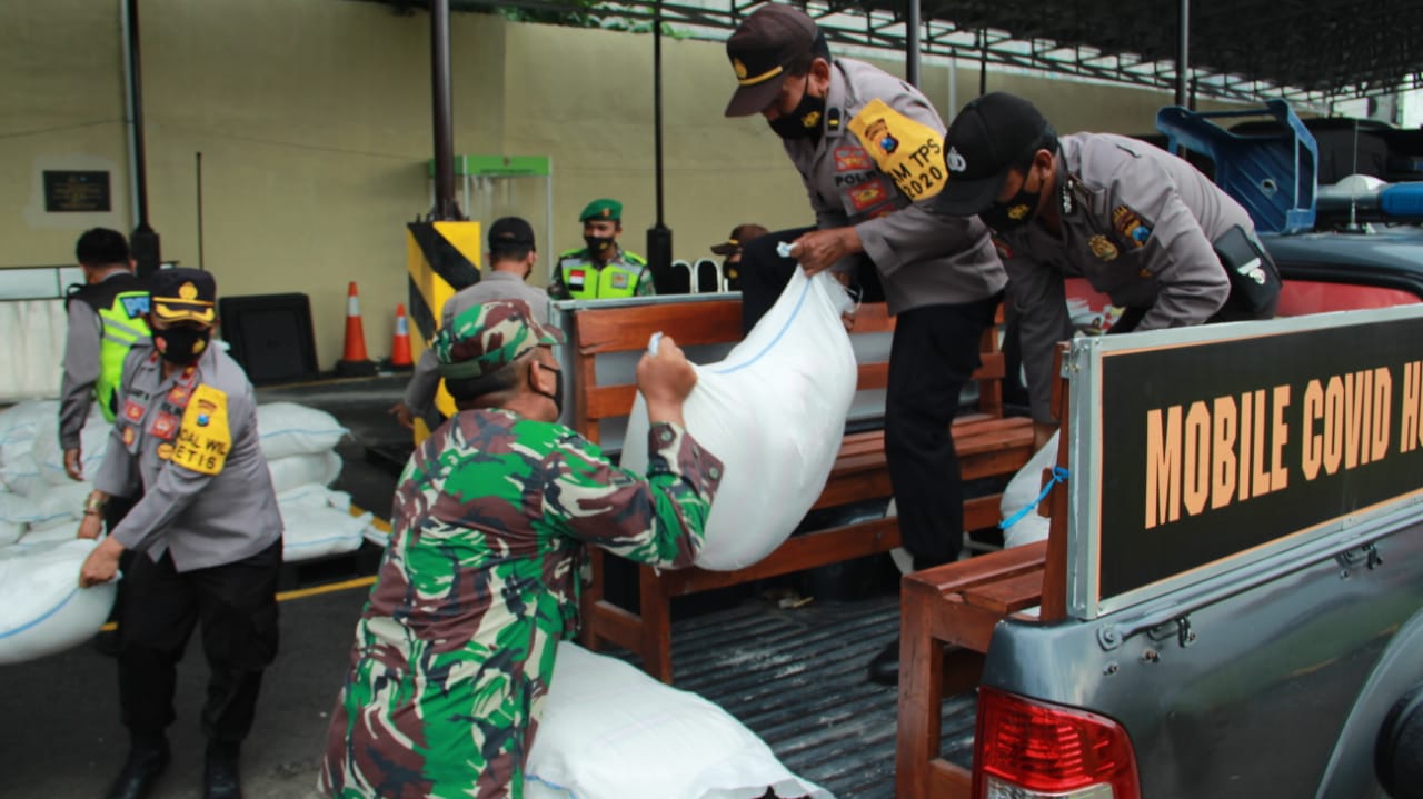 Polres Mojokerto Kota, diikuti oleh personel Dandim 0815 membagikan beras kepada masyarakat terdampak COVID-19 dan masyarakat tidak mampu. (Foto: umam ) 