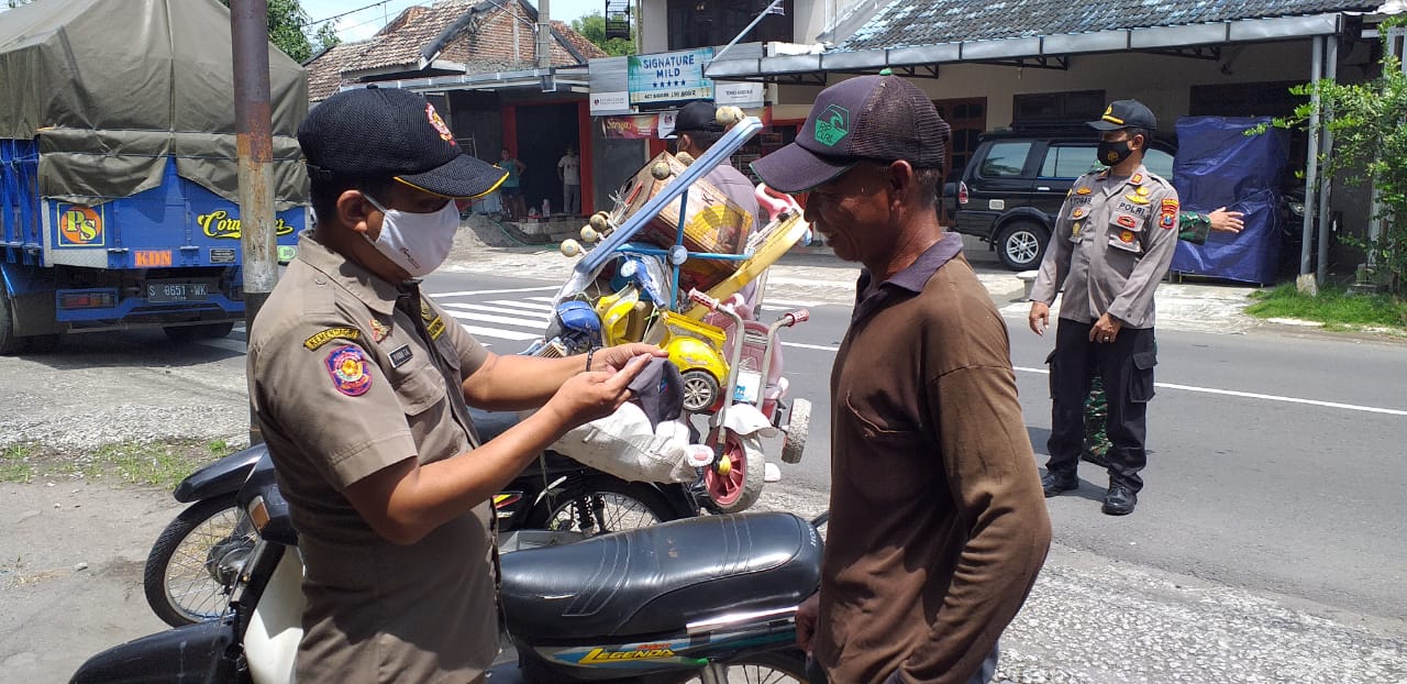 Salah seorang personel Satpol PP Jombang tengah memeriksa identitas pelanggar prokes dalam operasi non yustisi, Senin (25/1/2021).