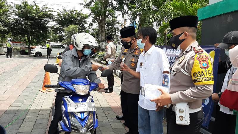 Kapolres Gresik AKBP Arief Fitrianto (kanan) bersama Ketua PWI Gresik M. Sholahudin membagikan masker kepada para pengguna jalan untuk peringatan Hari Pers Nasional (HPN) 2021 di Masjid Agung Gresik, Jumat (5/2/2021). | (TBK/Bacasaja.id)
