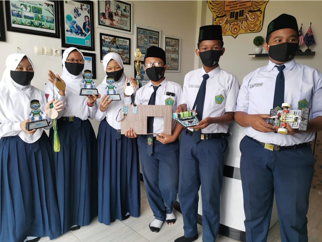 Para siswa siswi menunjukkan piala dan karya robotnya di Sekolah MTs Nurul Islam, Gresik (TBK/BACASAJA.ID) 
