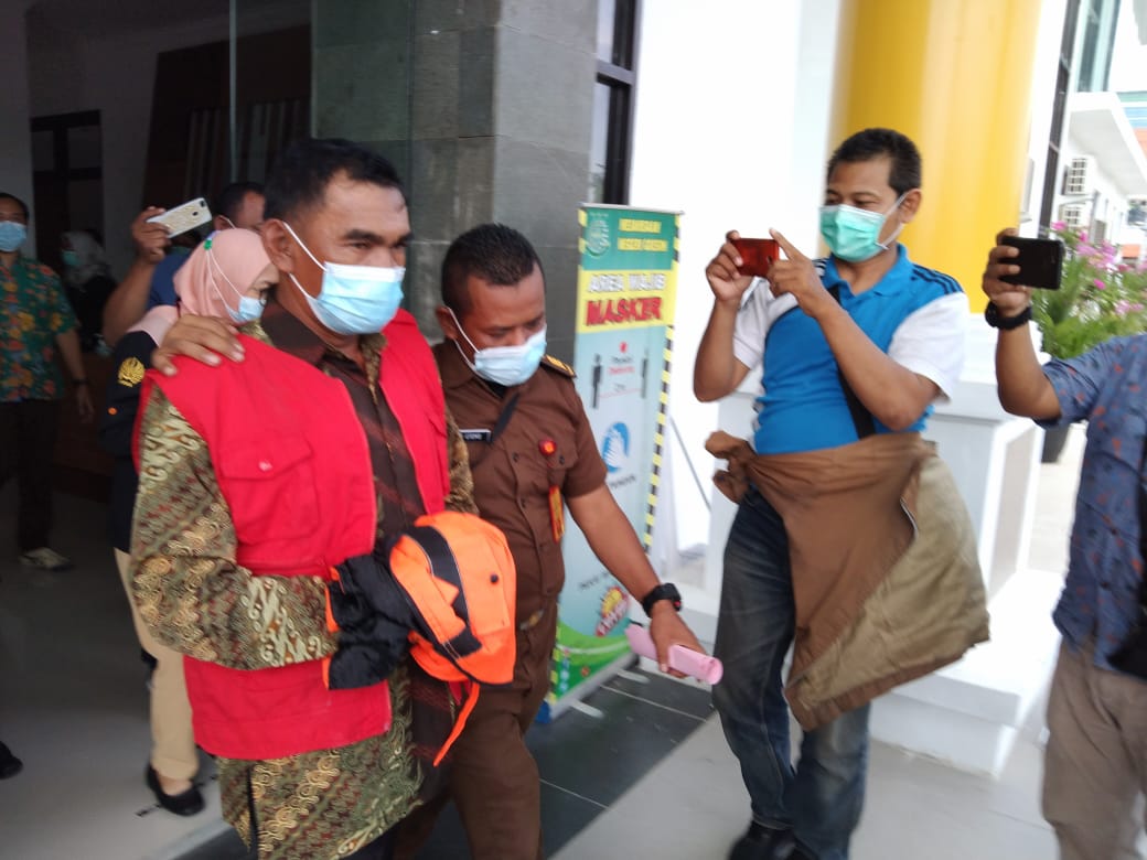Kepala Desa Dooro, Mat Ja'i saat digelandang petugas dari Kejari Gresik menuju mobil tahanan Kejari, Kamis (11/2/2021). (TBK/Bacasaja.id).