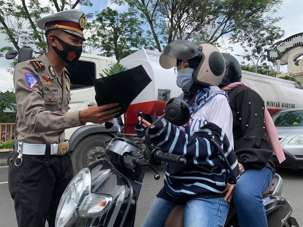 CIEEE: Salah seorang anggota Satlantas Polresta Sidoarjo mempersembahkan buket masker kepada wanita pengguna jalan, Selasa (16/2/2021). 