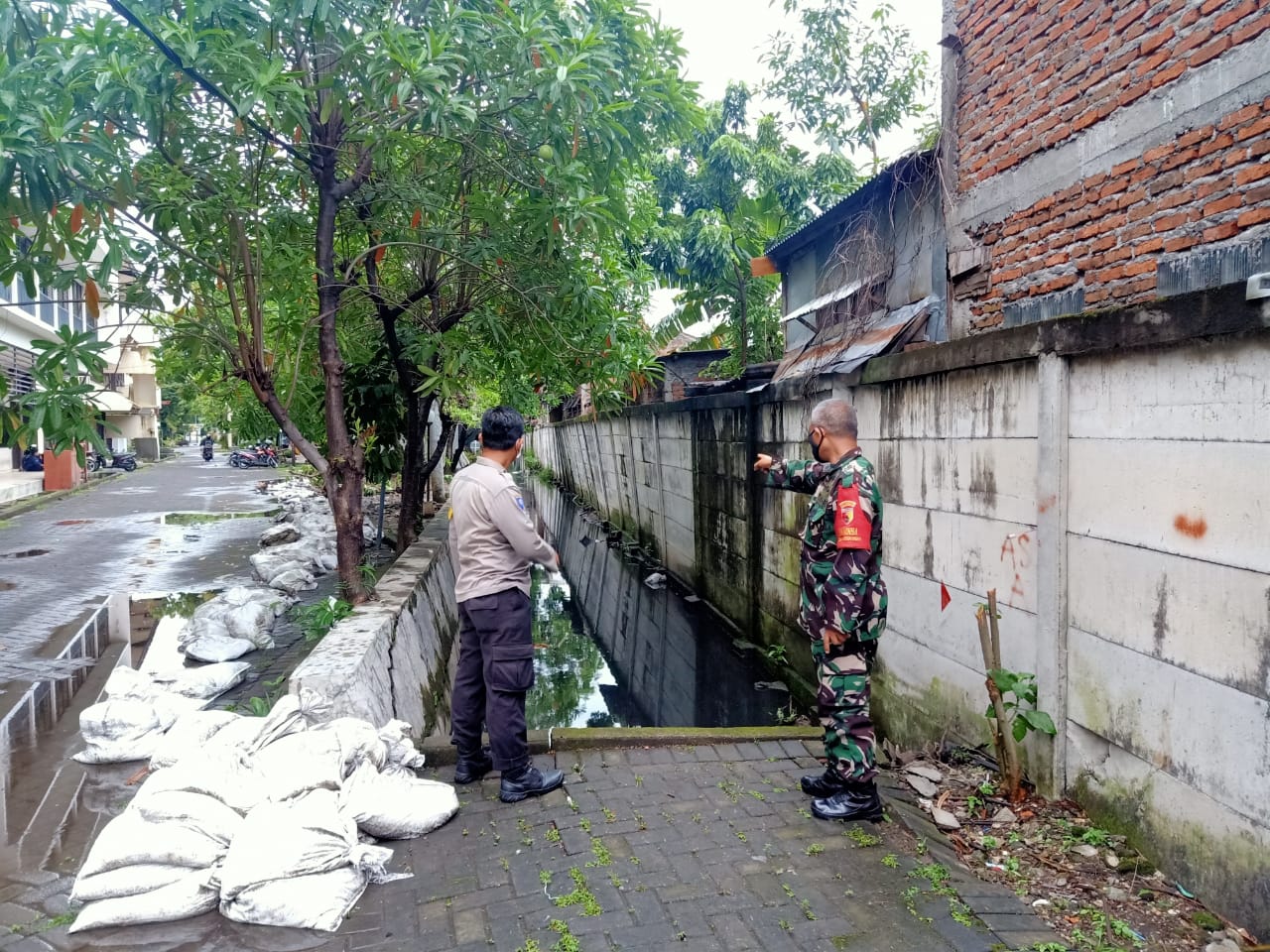 Babinsa Ketintang Sertu Sudrajat bersama Bhabinkantibmas Ketintang Bripka Heri saat memantau sungai di Unesa Ketintang Surabaya.