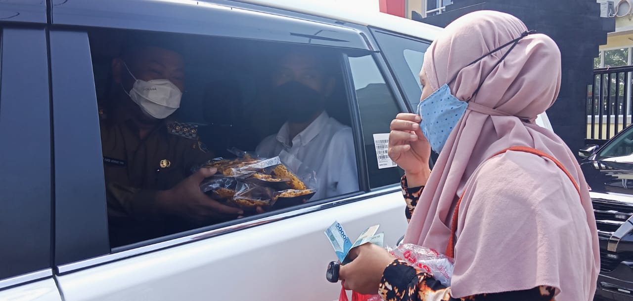 Himah saat mencegat mobil Bupati Gresik Gus Yani yang keluar Mapolsek Gresik usai apel kolaborasi dan menawarkan jajanan kripik rempeyeknya, Senin (15/3/2021).