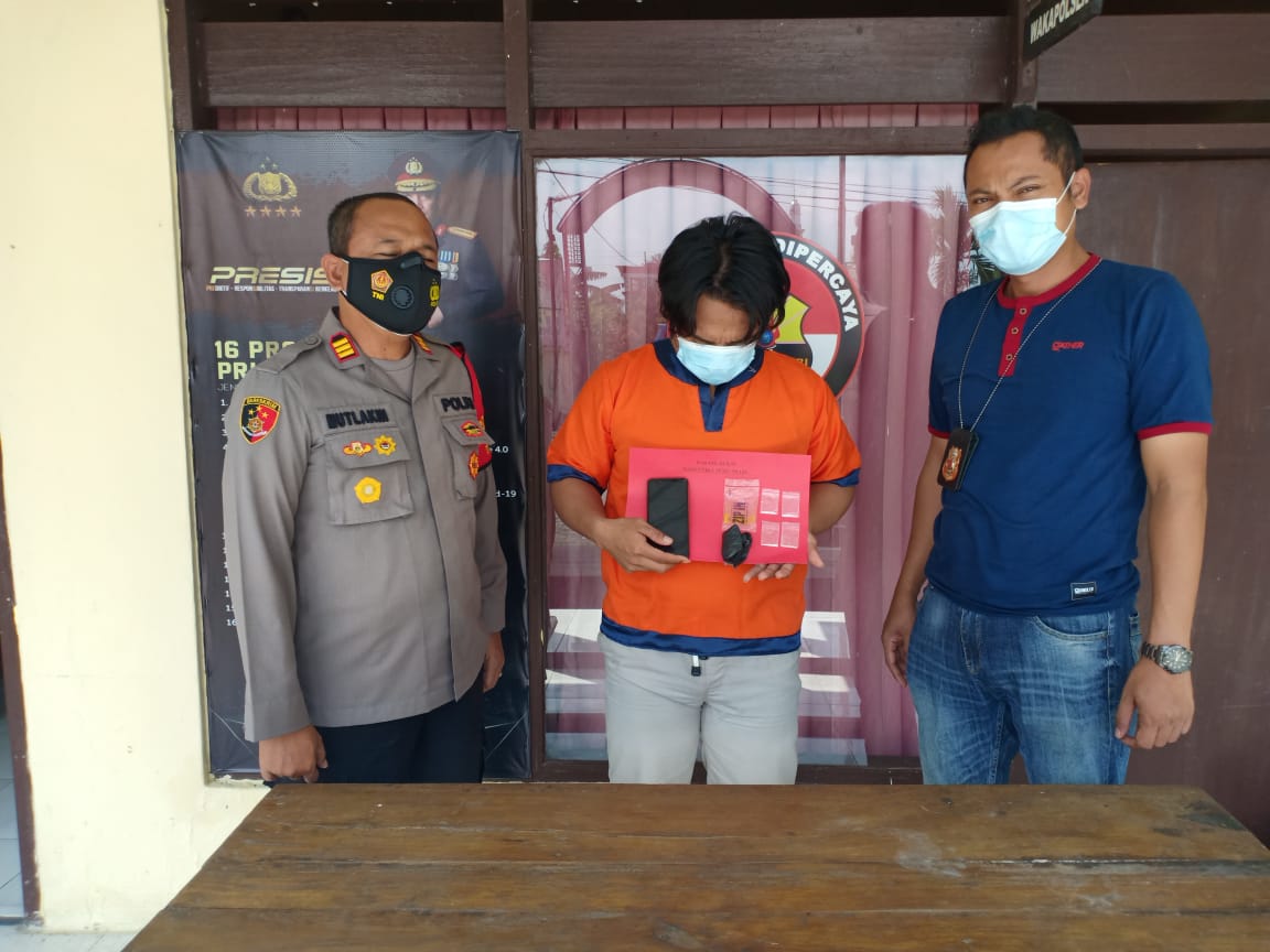 Dian Agus Prayitno memegang barang bukti saat diamankan Polsek Dukun Gresik, Jumat (19/3/2021).