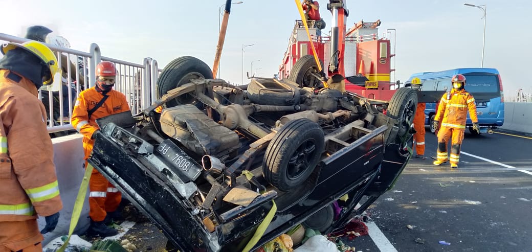 Petugas PMK Surabaya mengevakuasi mobil pengangkut buah yang terguling di Jembatan Suramadu, Jumat (19/3/2021). Foto: Istimewa