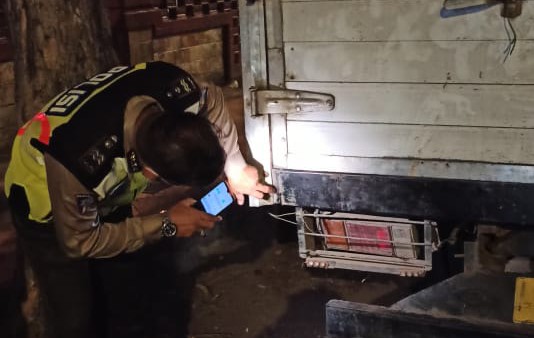 Polisi menunjukkan bekas bagian belakang mobil yang tertabrak motor korban.
