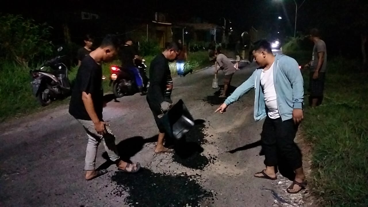 Syahrul Munir bersama pemuda desa gotong royong memperbaiki jalan dengan menambal yang berlubang, Kamis (19/4/2011) malam. 