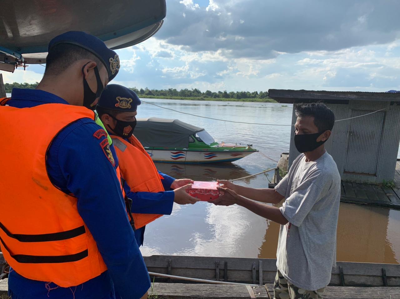 Anggota Satpolair Polres Hulu Sungai Utara membagikan takjil ke warga pesisir pada Sabtu petang (24/4).