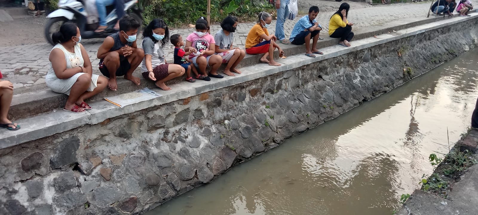 Warga disekitar sungai memberi ikan yang ditabur di sungai.