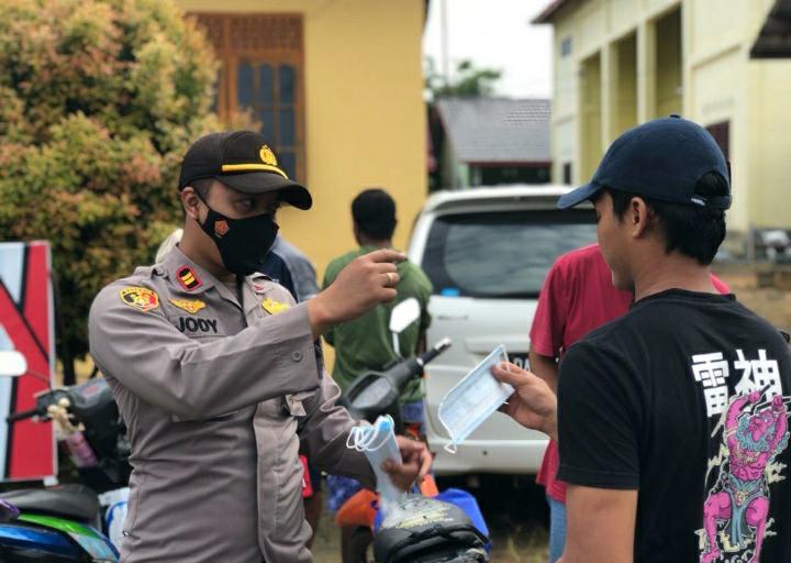Kapolsek Angsana Iptu Jody Dharma bagikan masker kepada pelanggar prokes usai jalani sanksi sosial.