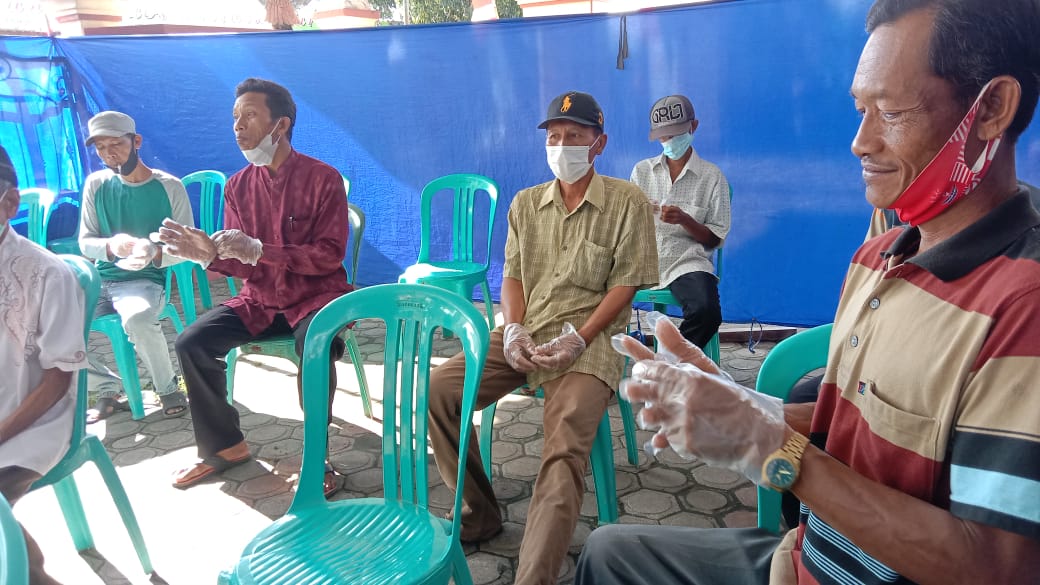 Menggunakan sarung tangan, warga antri menggunakan hak pilihnya dalam Pilkades Desa Waung.