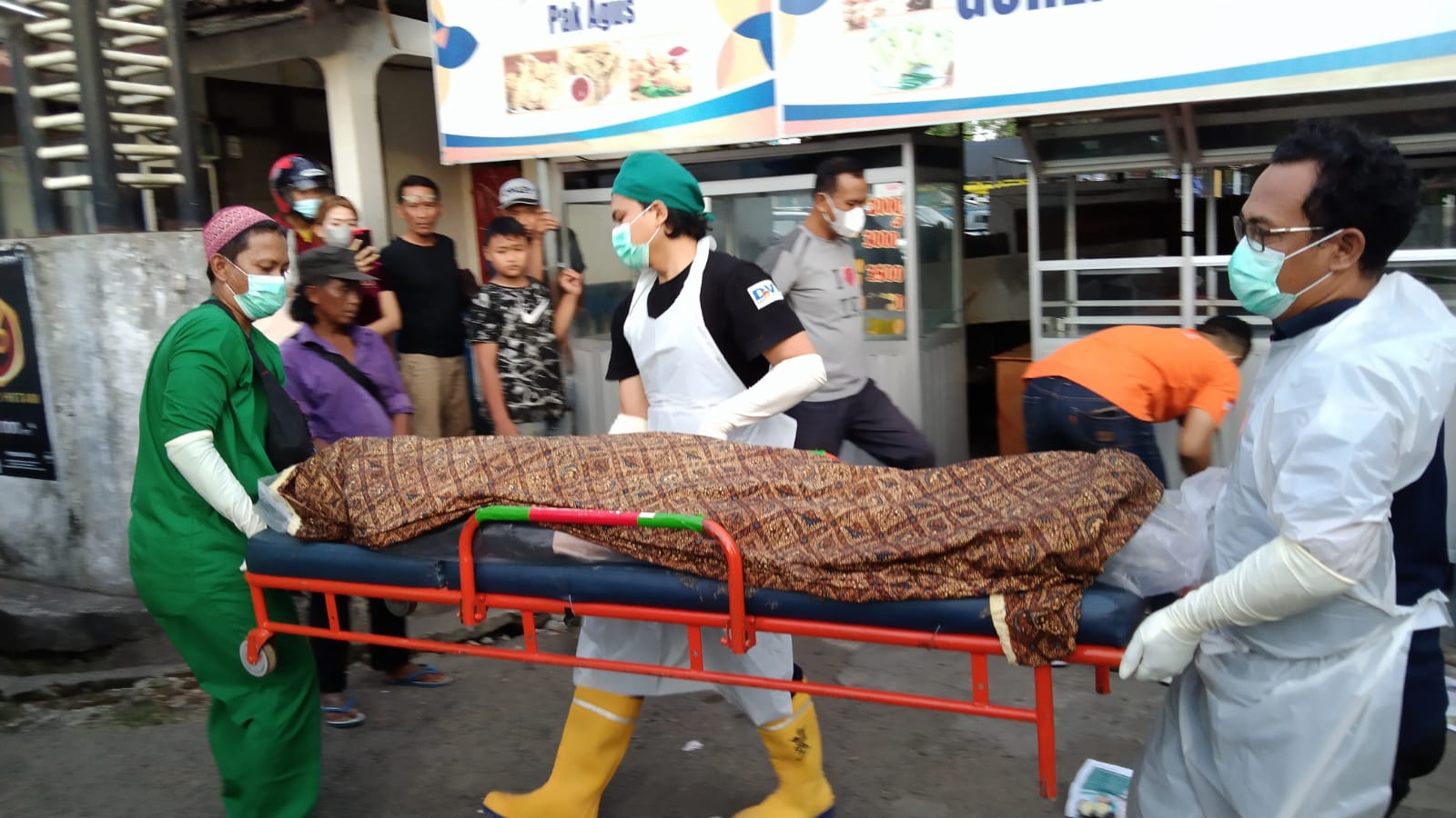 Petugas saat mengevakuasi jenazah pria tua di Pujasera Ngamplak Tulungagung.