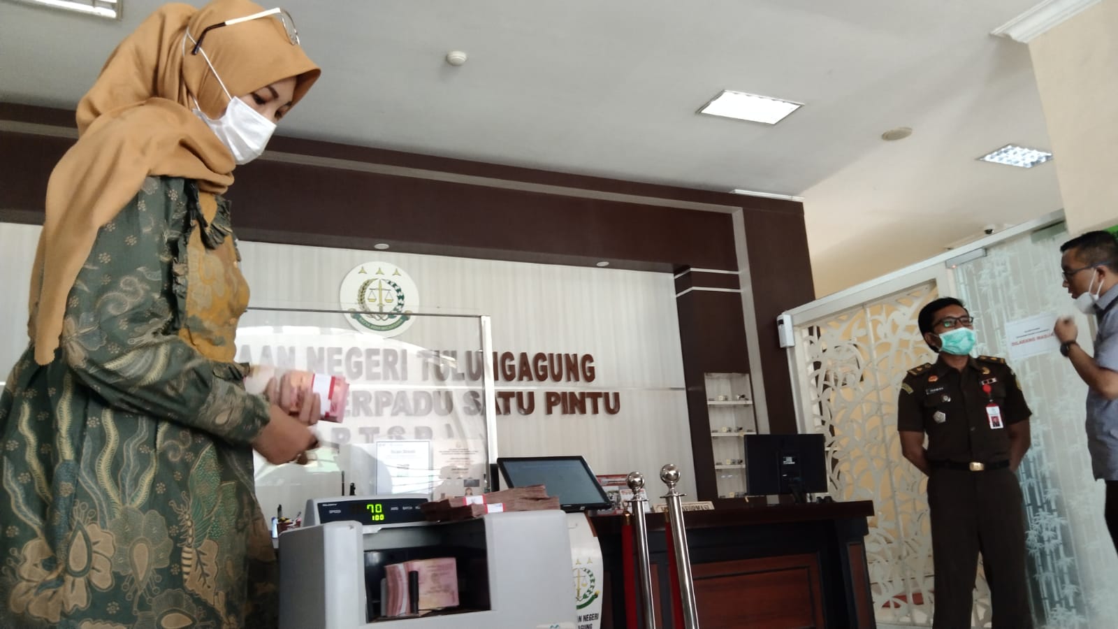 Uang dari PT. Kia Graha dihitung sebelum dititipkan ke bank.