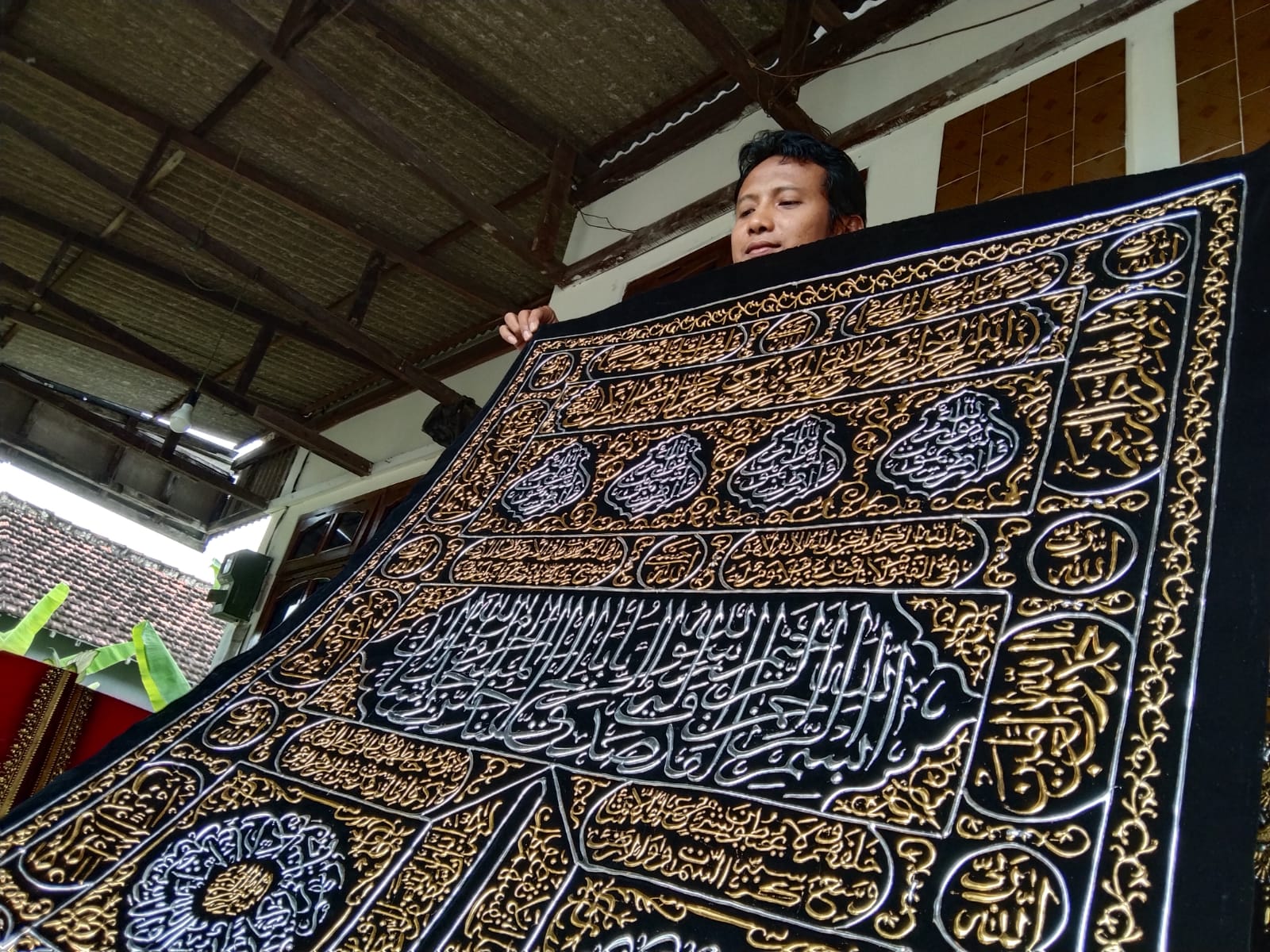 Andik saat membuat kaligrafi menggunakan kertas Prada.