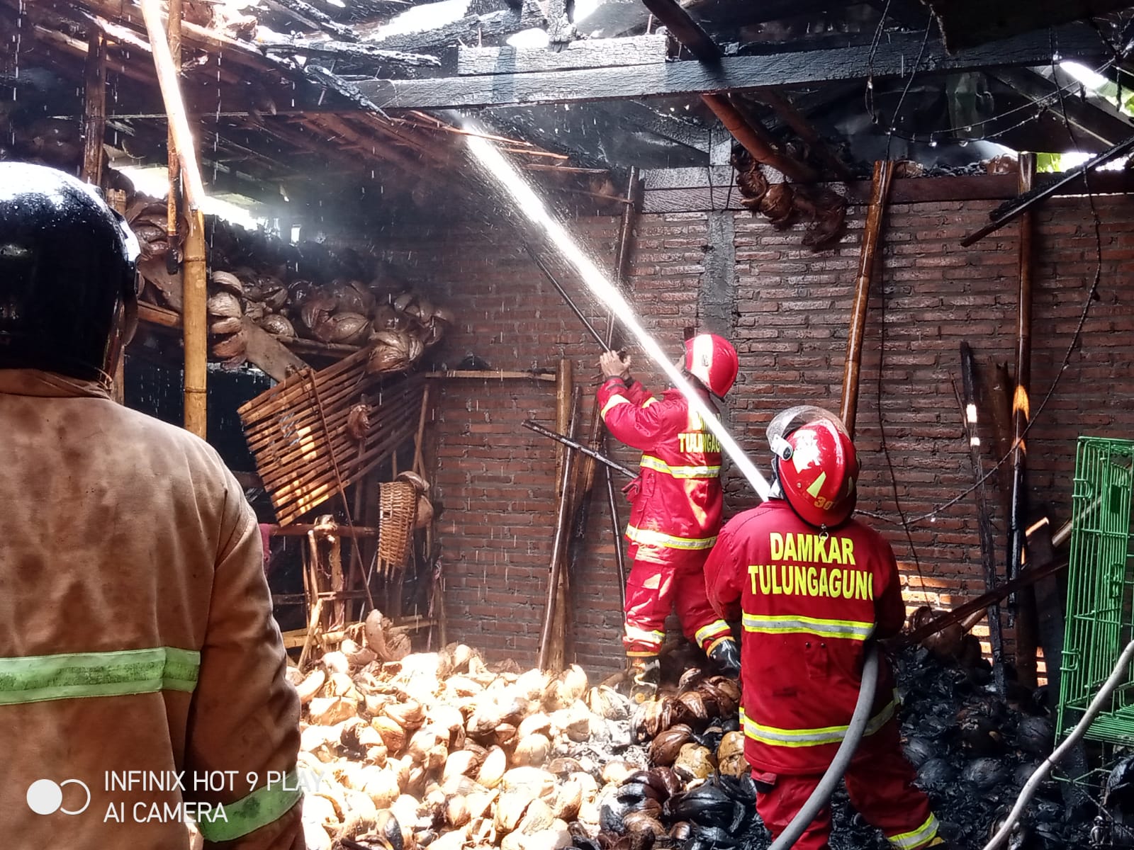 Petugas Damkar melakukan pembasahan serabut kelapa yang terbakar.