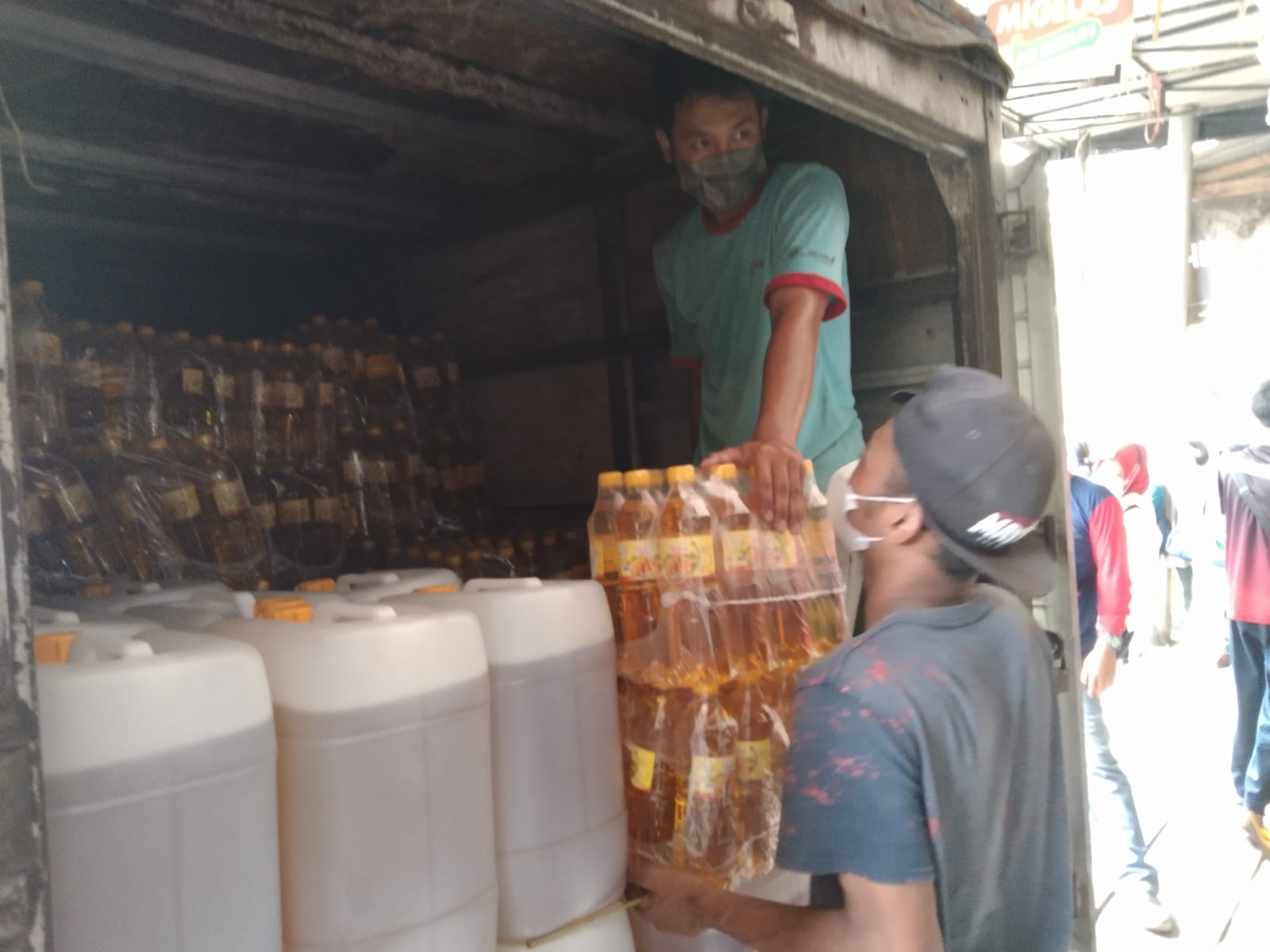 Pekerja sedang menurunkan minyak goreng dari mobil pengangkut di salah satu toko.