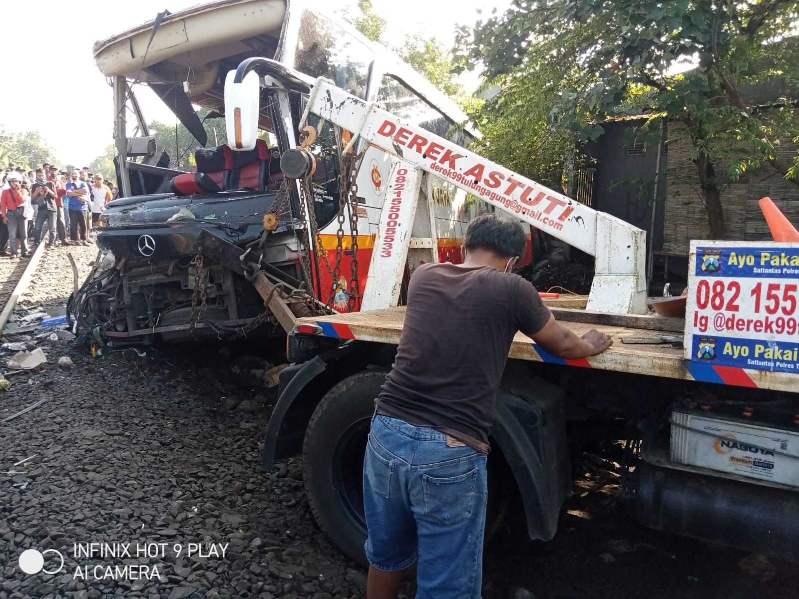 Mobil derek mencoba menarik badan bus yang terjebak di tanah lembek.