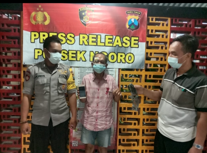 Tersangka Muhammad Nur diapit petugas kepolisian.