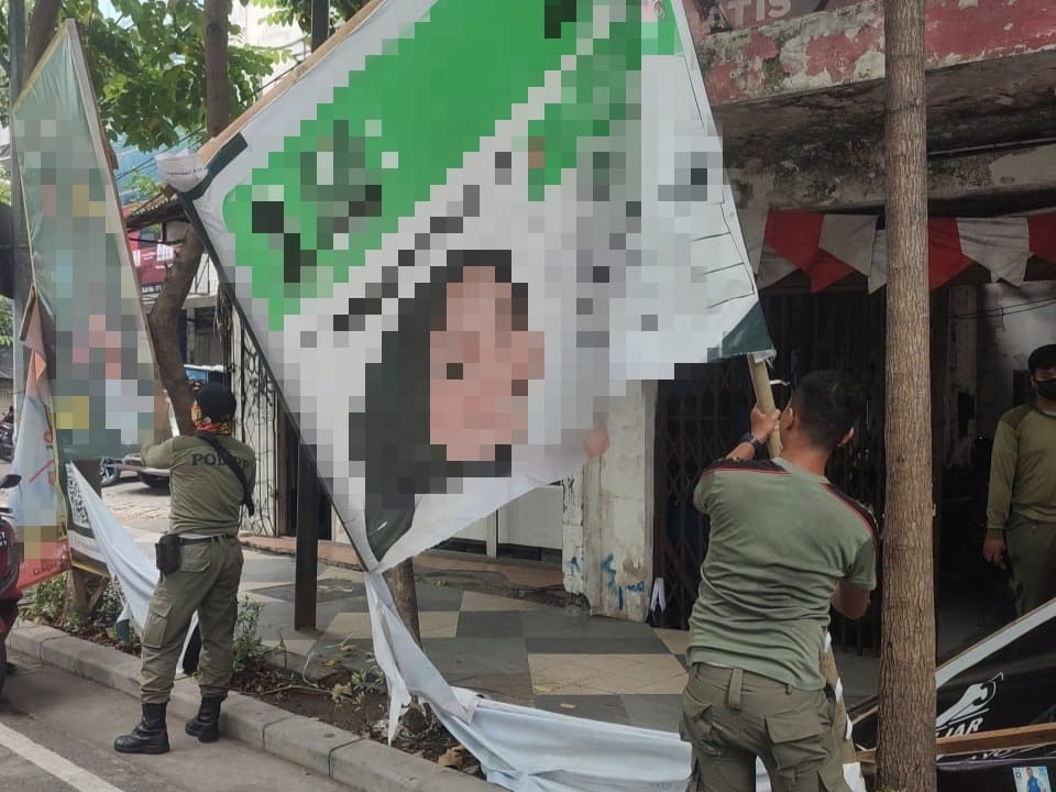 Satpol PP Surabaya menertibkan alat peraga kampanye (APK) yang menjamur di tepi jalan di Kota Surabaya. 