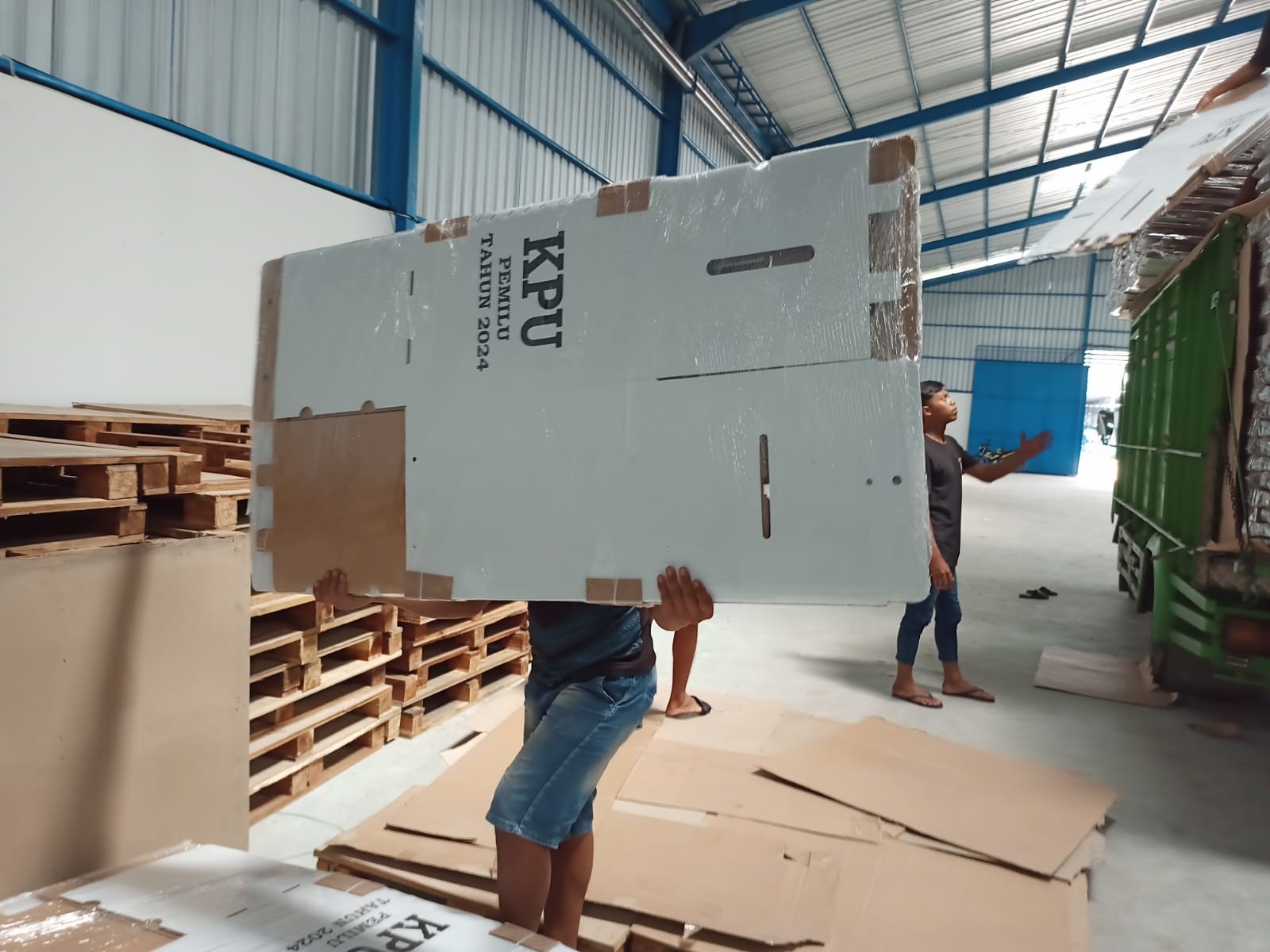 Pekerja sedang menurunkan kotak suara logistik Pemilu 2024.