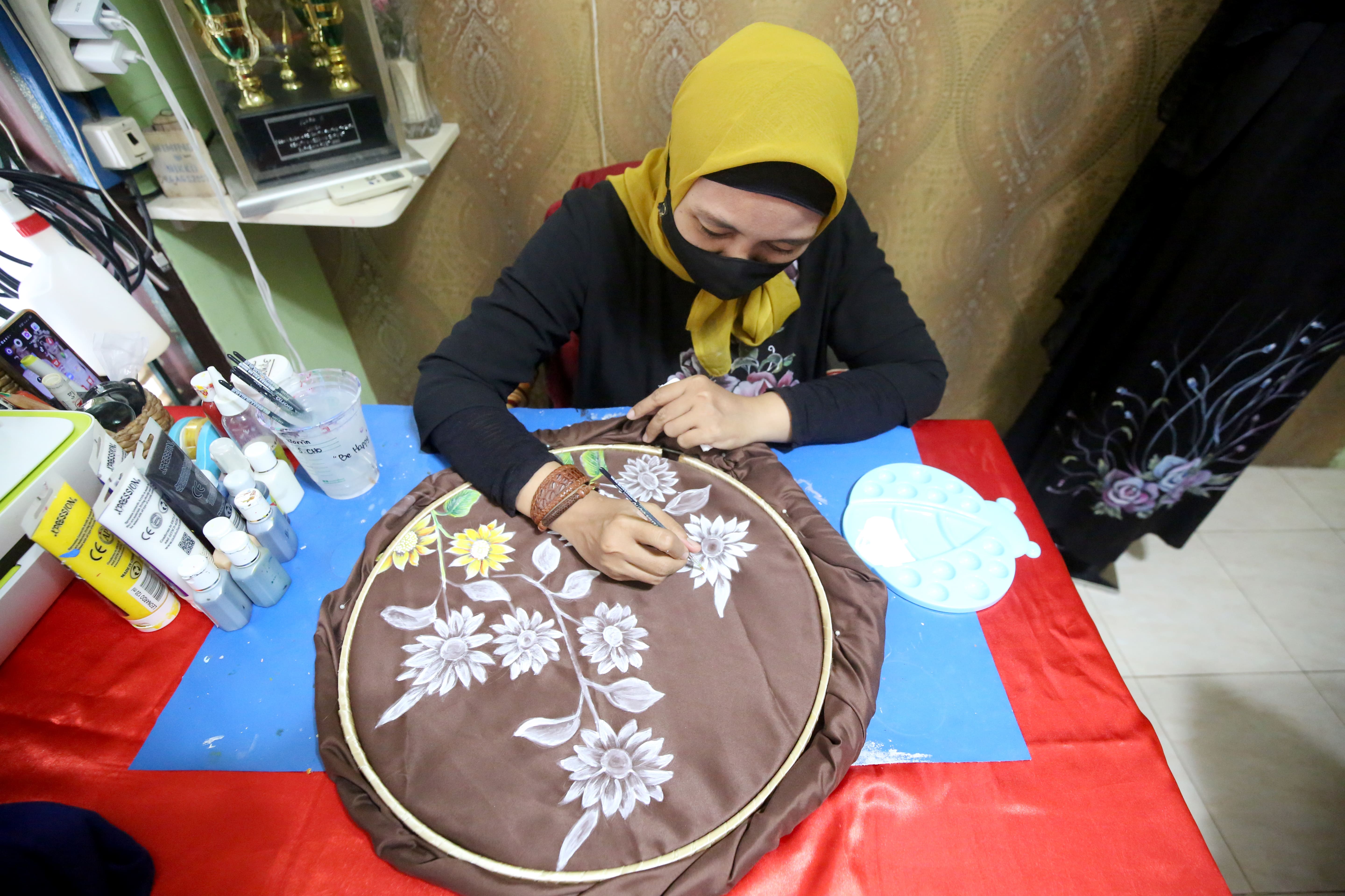 Pegawia UMKM Verrinza Design & Art saat melukis pesanan jilbab