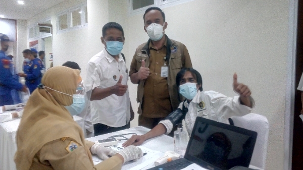 Ketua PWI Gresik Sholahudin dicek darah didampingi Kadinkes, Syaifuddin Ghozali pada vaksinasi, Selasa (23/2/2021) di Mapolres Gresik. (TBK/Bacasaja.id)
