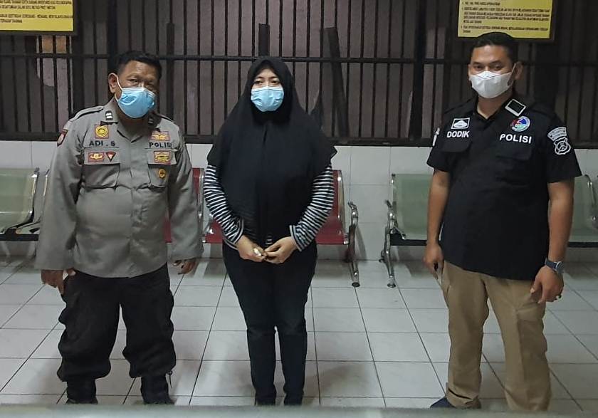 Tersangka Arizanty diapit dua petugas kepolisian.