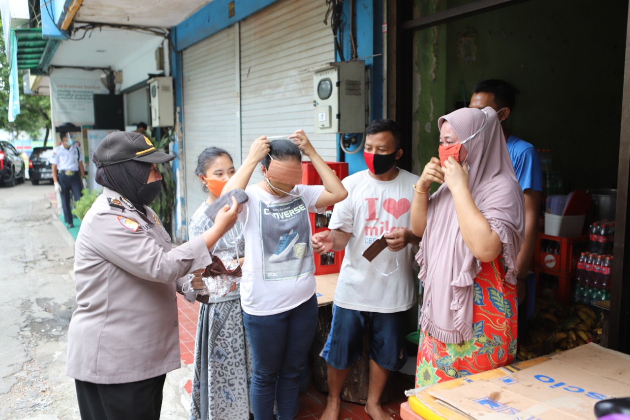 Salah seorang Polwan memberikan masker kepada warga di Jalan Kalianget, Rabu, 3 Februari 2021.