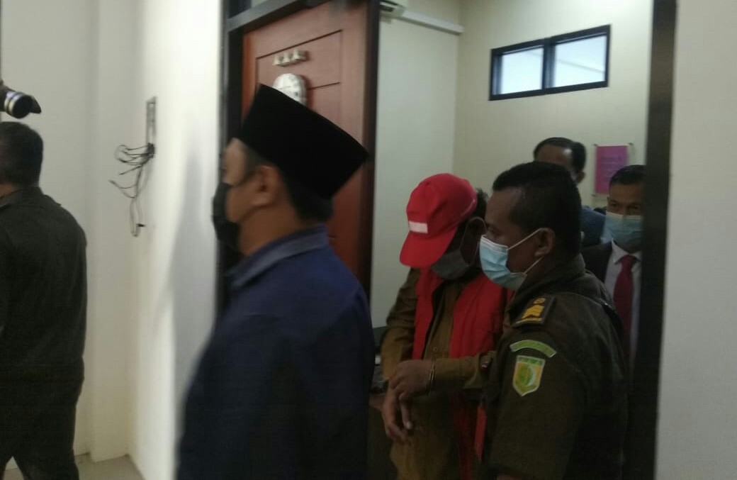 Tersangka Camat Duduksampeyan, Suropadi (rompi orange bertopi merah) saat di gelandang menuju mobil tahanan Kejari Gresik, Senin (15/2/2021). (TBK/Bacasaja.id)