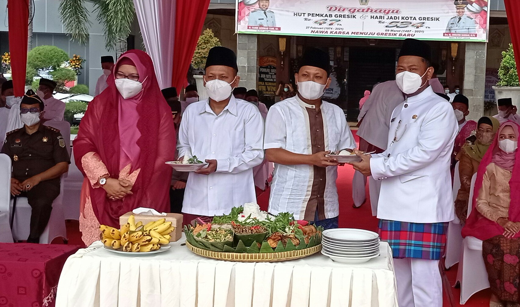 Bupati Gresik, Fandi Akhmad Yani (kanan) memberikan potongan tumpeng kepada dua Kepala Desa saudara kembar di HUT Gresik, Selasa (9/3/2021).