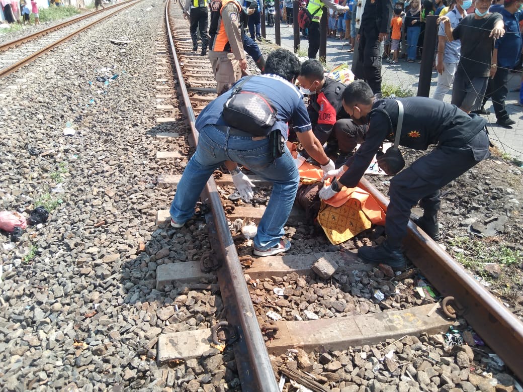 Petugas saat mengevakuasi jenazah perempuan berusia 12 tahun yang tewas usai tersambar kereta api