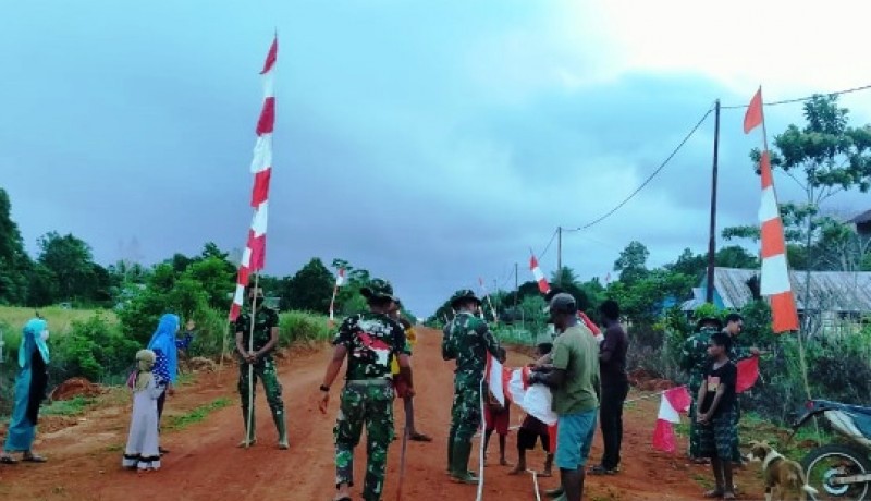 Warga bersama satgas Pamtas Yonif 611/Awang Long memasang bendera merah putih di sepanjang kalan kampung Baidub Kabupaten Merauke wilayah perbatasan RI dengan Papua Nugini. (Pendam XVII/Cenderawasih)