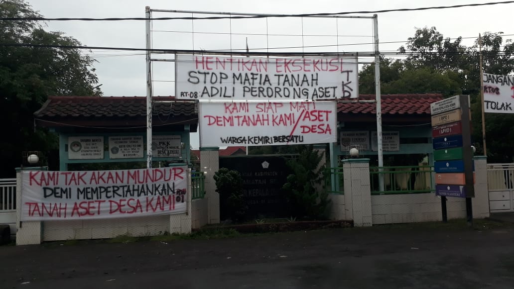 Spanduk dan pamflet bernada protes terhadap rencana eksekusi Balai Desa Kemiri, Sidoarjo