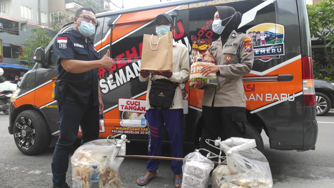 Jajaran Polrestabes Surabaya memberikan hadiah kepada warga yang taat prokes di depan mobil senyum. 