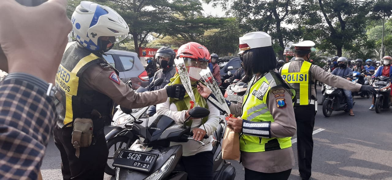 Petugas Satlantas Polrestabes Surabaya membagikan bunga kepada para pengendara, Senin (26/10)