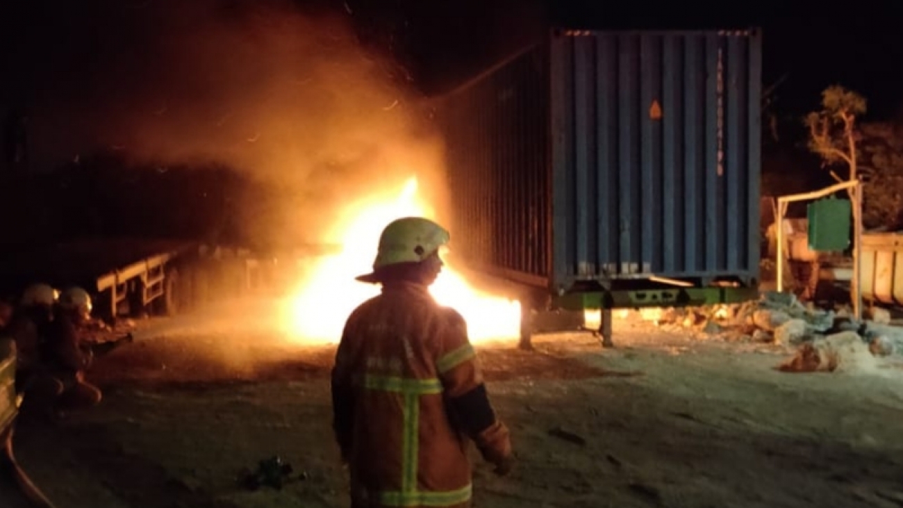 Petugas memadamkan kontainer yang terbakar.