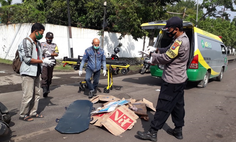 Petugas kepolisan sedang mengevakuasi korban kecelakaan di jalan raya Sukomulyo, Manyar, Gresik, Jumat (26/2/2021). (FOTO TBK/BACASAJA.ID)